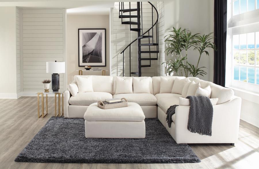 Set in a modern home with hardwood floors and grey colors a fluffy cushion white sectional sofa set with throw rug and blanket both dark grey.