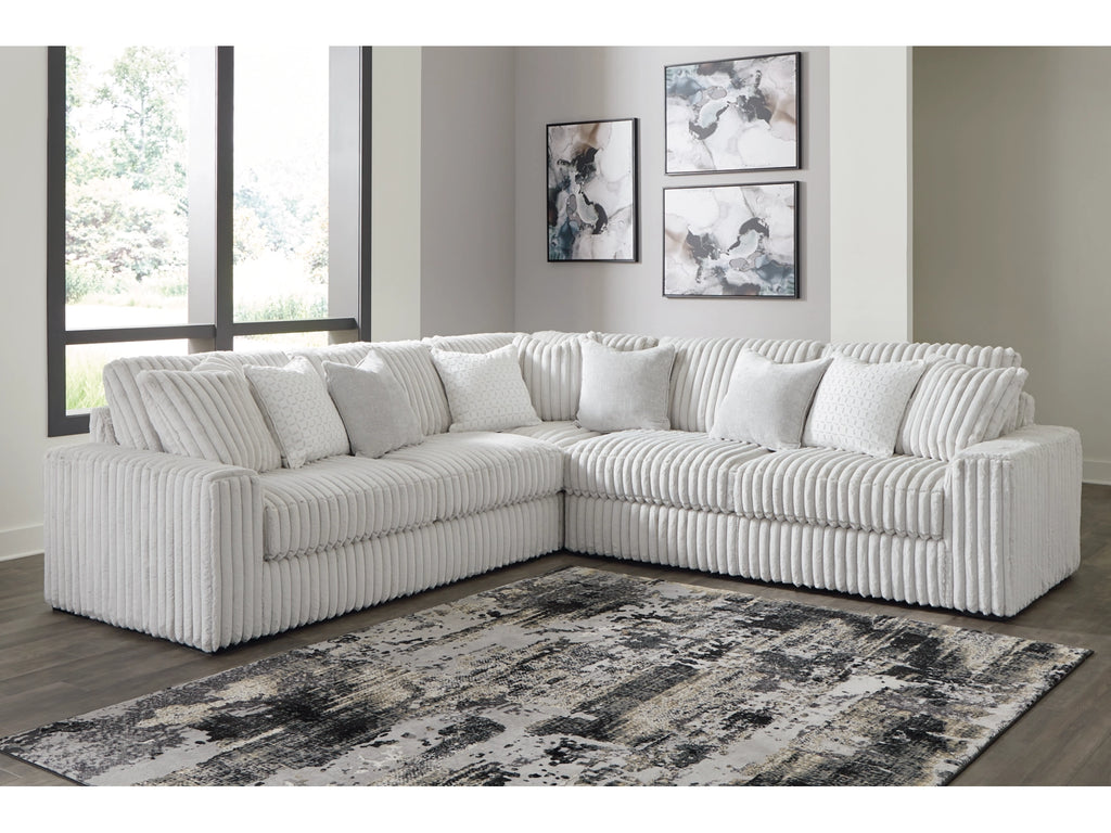 Light grey sectional sofa in a living room with abstract art on the wall.