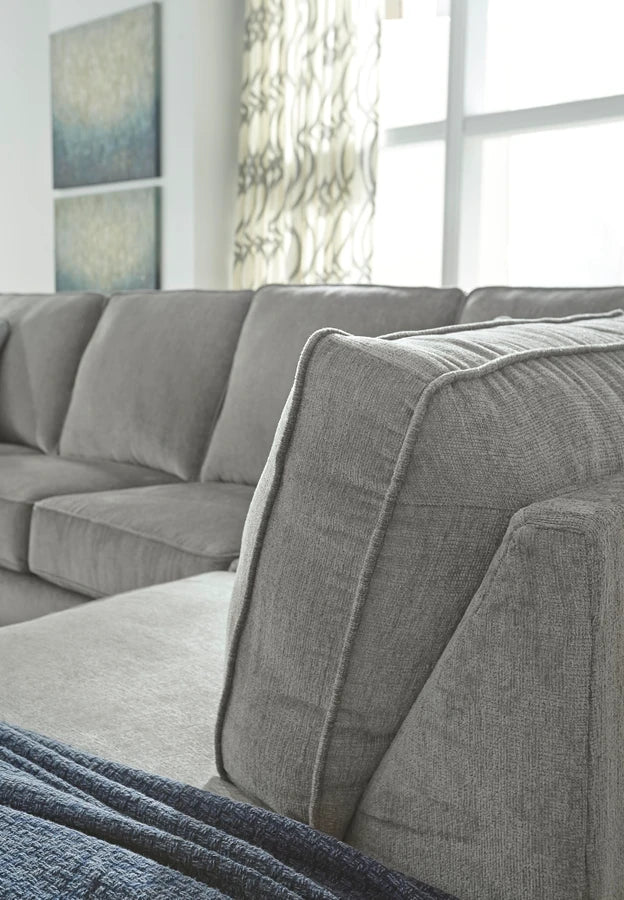 Close-up view of gray upholstered sectional sofa cushions showing textured fabric, plush back cushions, and modern piping detail.