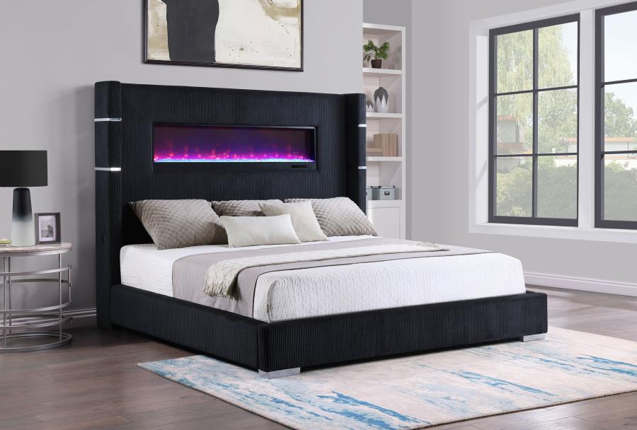 Modern bedroom with a black upholstered bed featuring an electric fireplace.