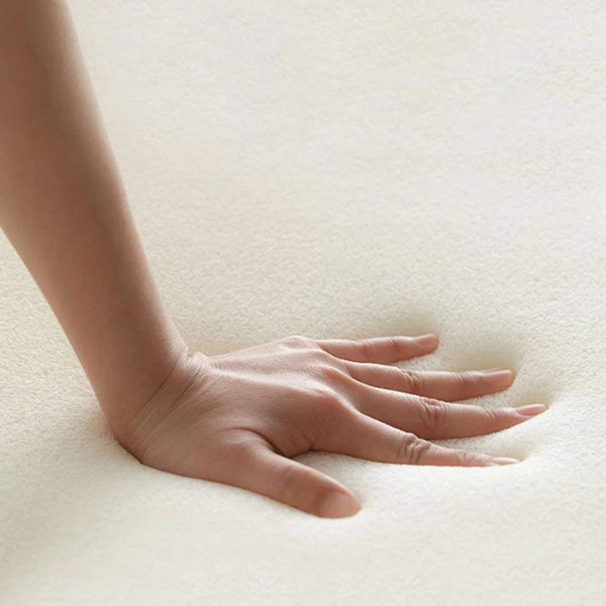 Hand pressing into white memory foam cushion