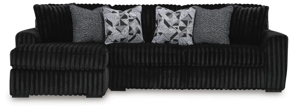 Black ribbed sectional sofa with patterned cushions on a white background