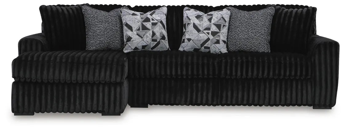 Black ribbed sectional sofa with patterned cushions on a white background