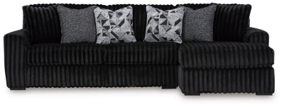 Black ribbed sectional sofa with patterned cushions on a white background