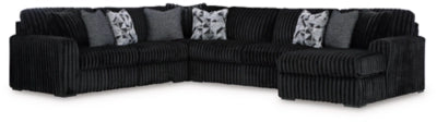 Black sectional sofa with patterned cushions on a white background