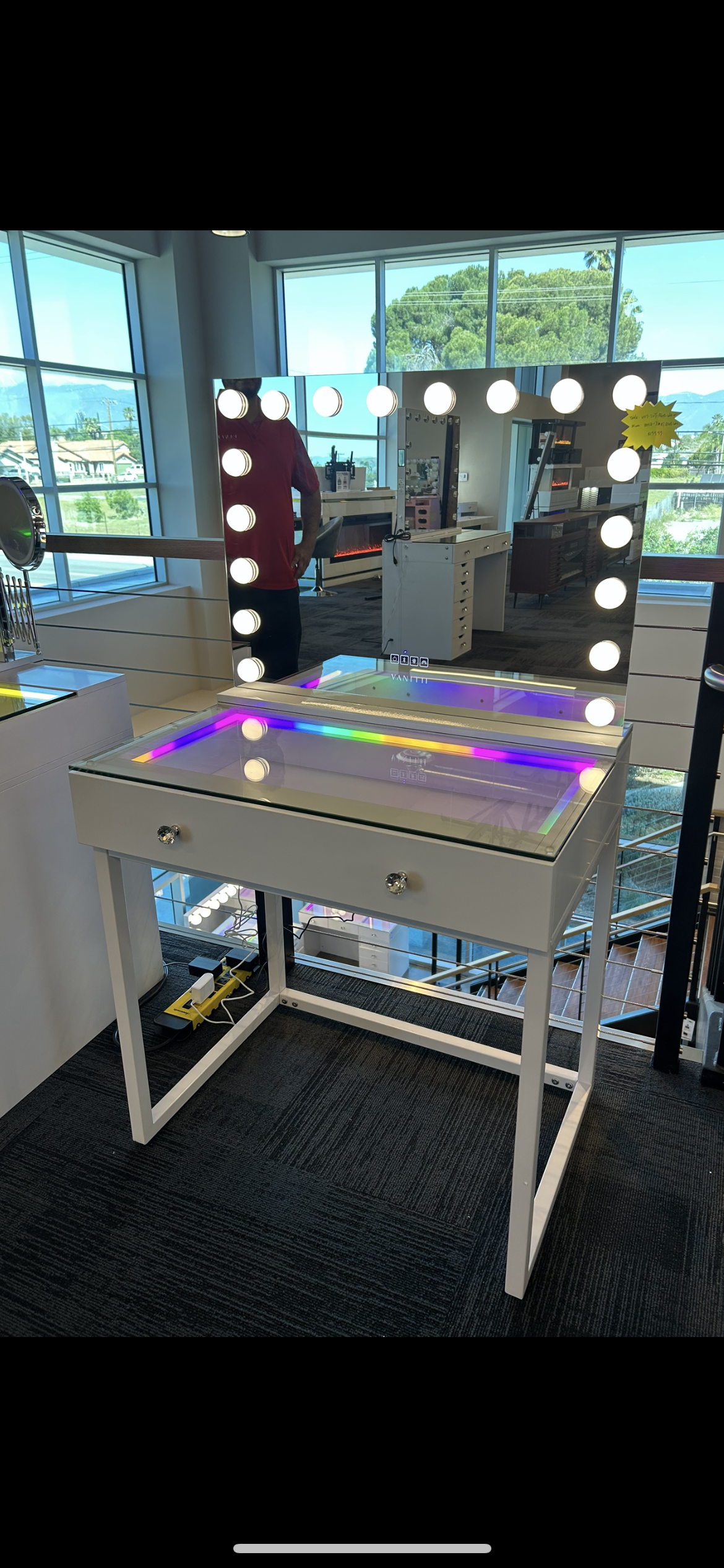 Makeup vanity with mirror and lights in a room with large windows.