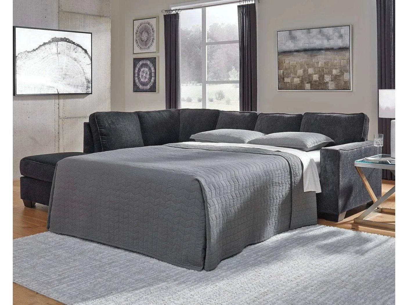 Gray sectional sofa in a living room with large windows and wall art.