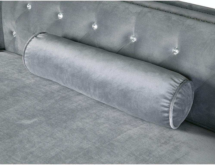 Gray tufted sofa with cylindrical backrest pillow on a matching gray fabric background