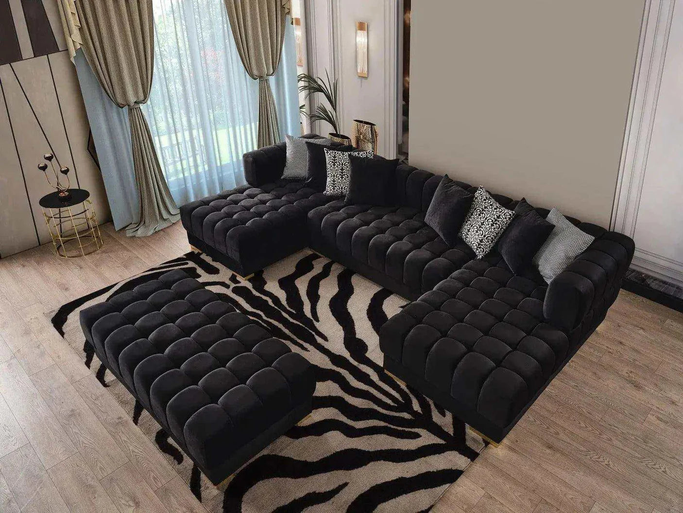 Black tufted sofa with ottoman on a zebra print rug in a room with curtains and decor.