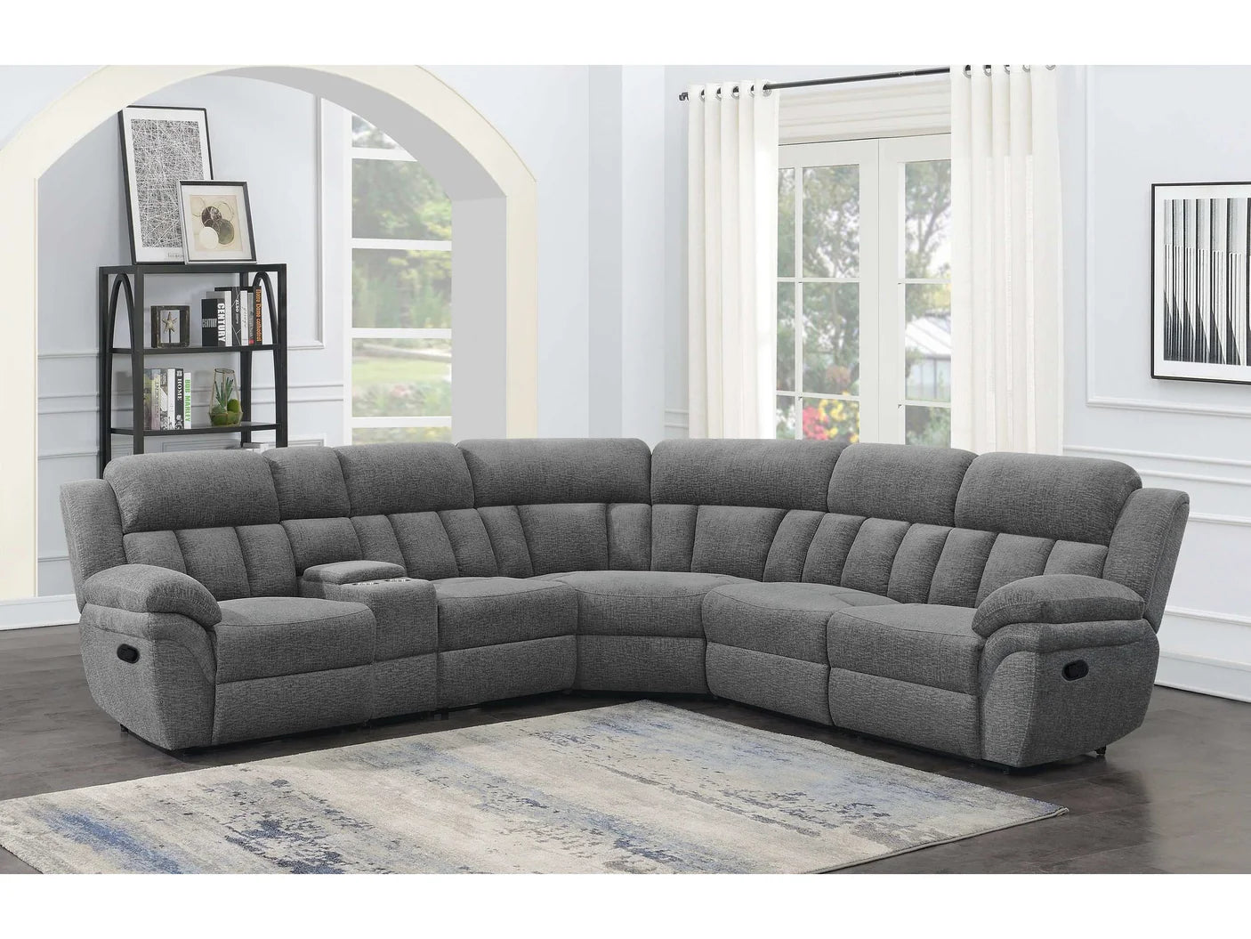 Gray sectional sofa in a living room setting with a rug and window.
