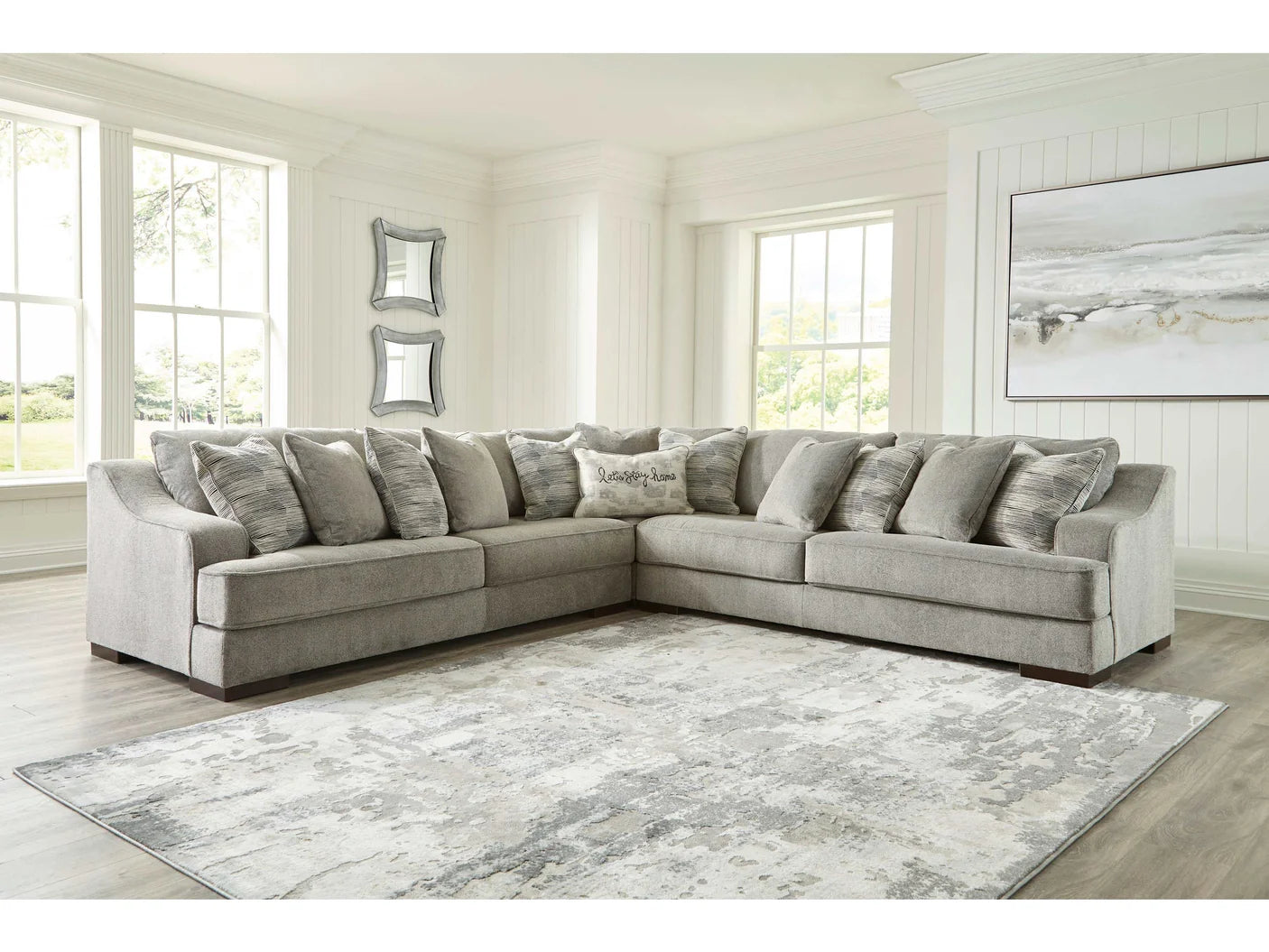 Gray sectional sofa in a living room with large windows and decorative mirrors.