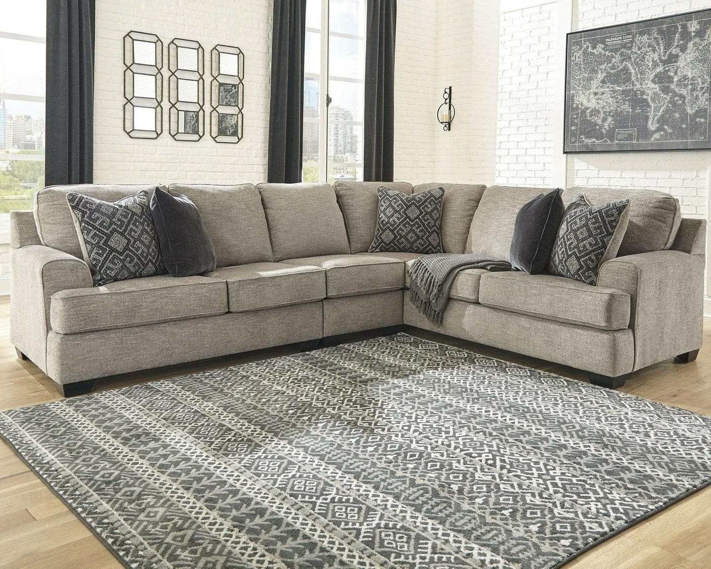 Gray sectional sofa with patterned cushions on a geometric rug in a living room.