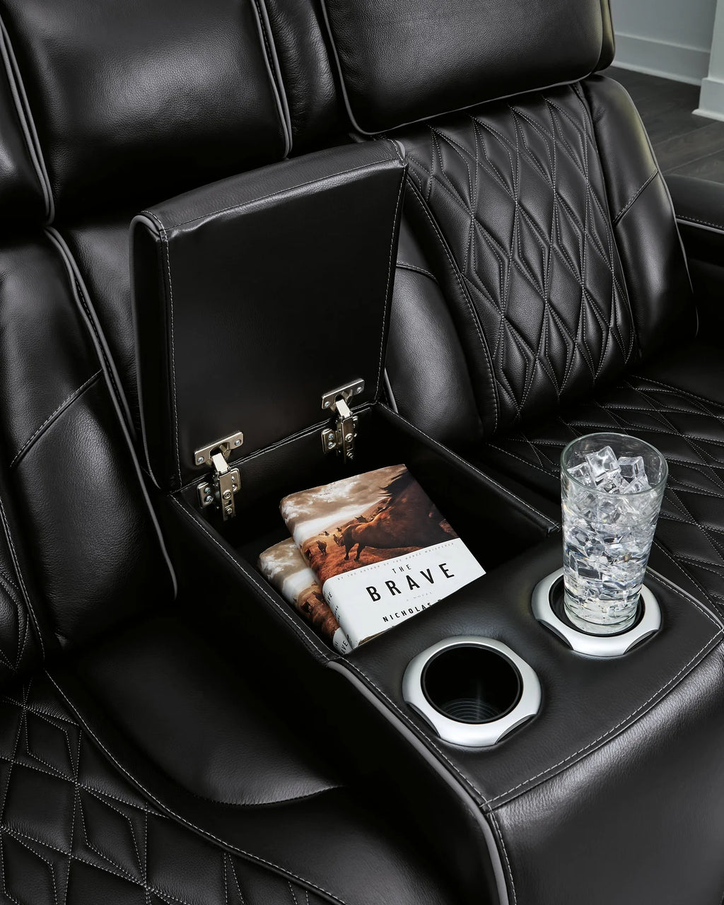Close up of storage and cupholders on black leather couch.