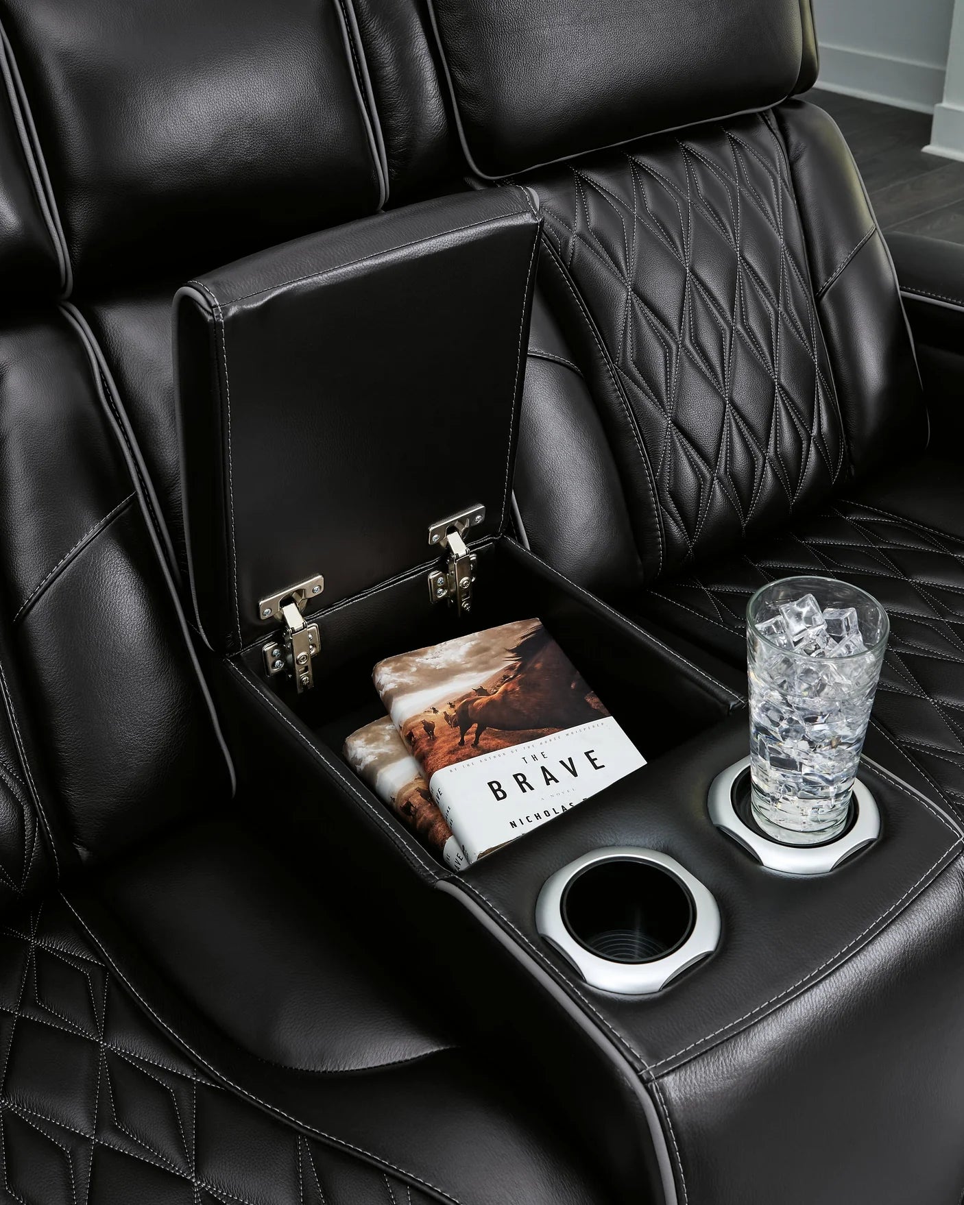 Close up of storage and cupholders on black leather couch.