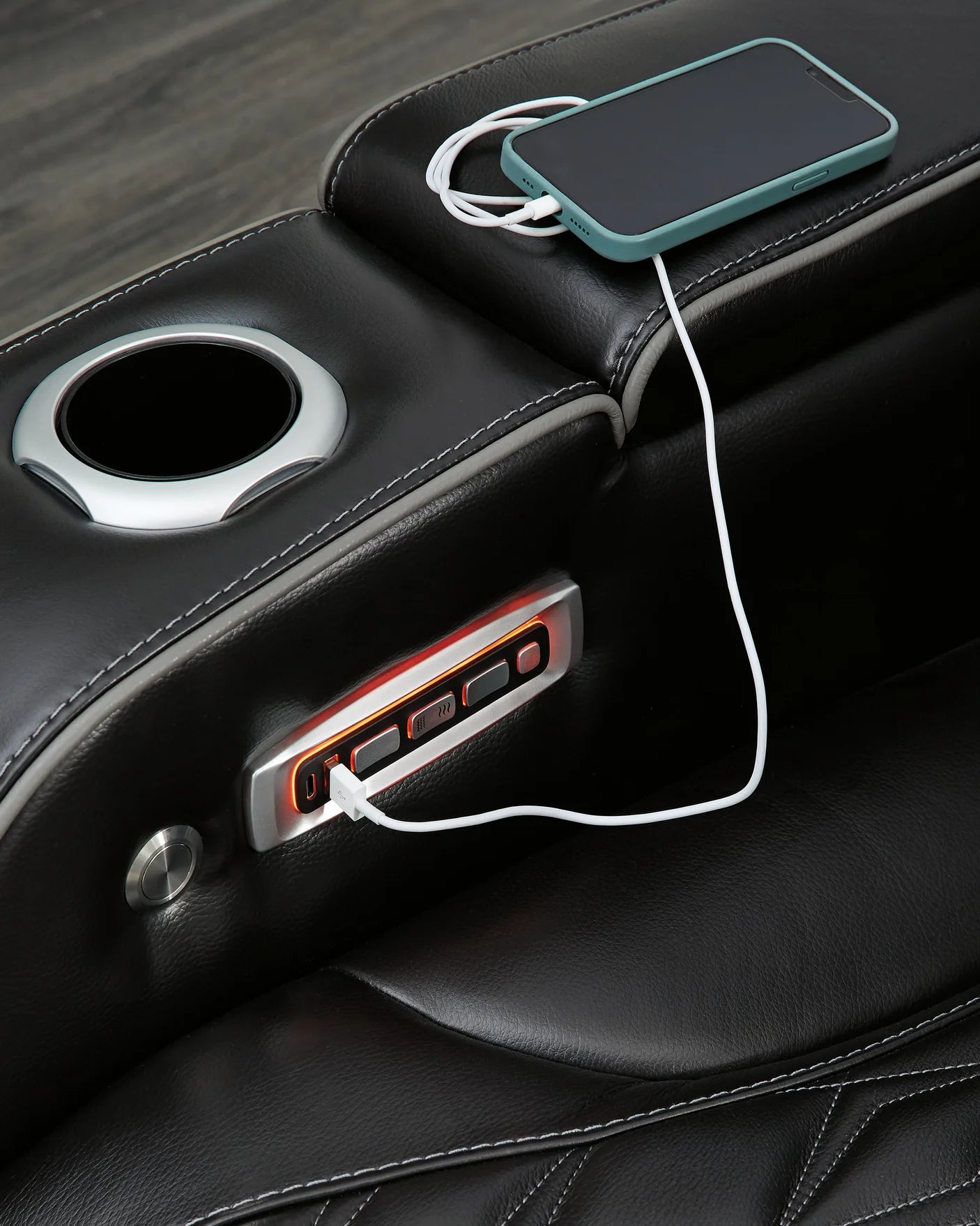 Close up of a phone charging through a black leather couch.