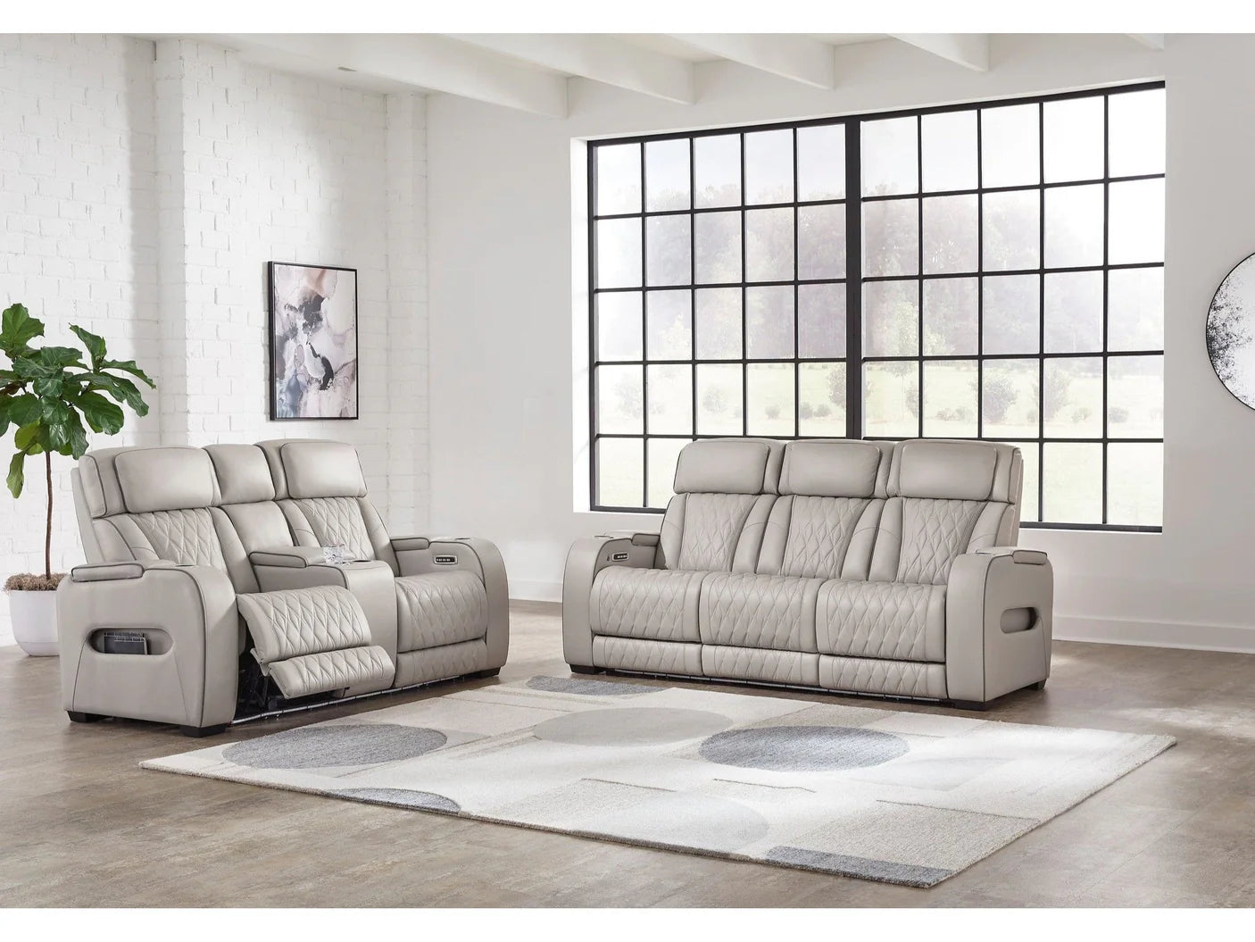 Grey recliner sofa set in a modern living room with large windows.