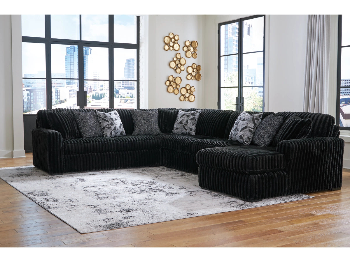 Black sectional sofa in a room with large windows and decorative wall art.