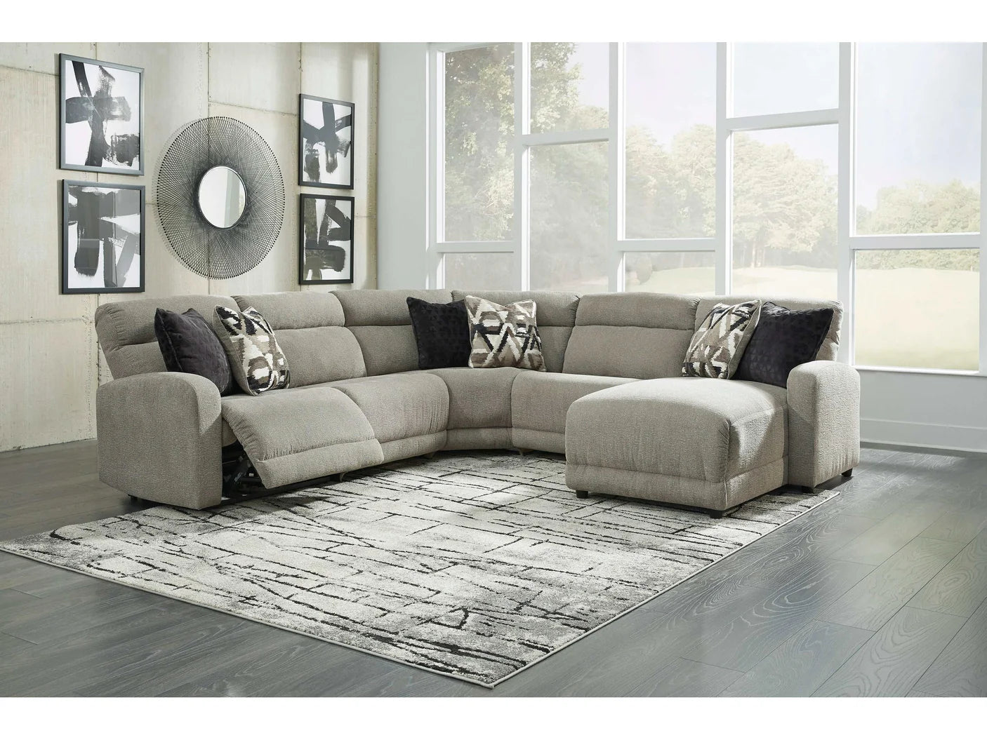 Gray sectional sofa in a living room with large windows.