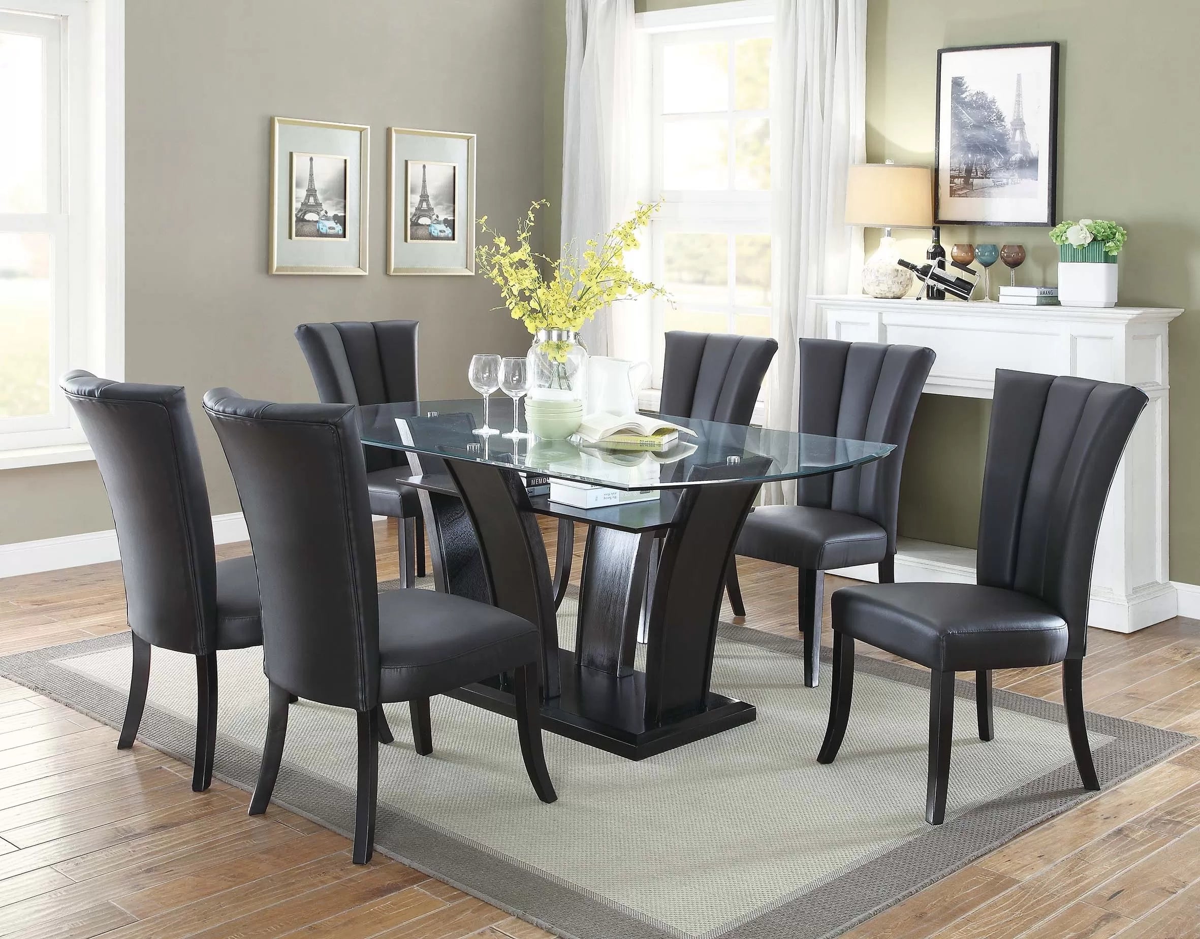 Dining room with a glass table and black chairs on a wooden floor.