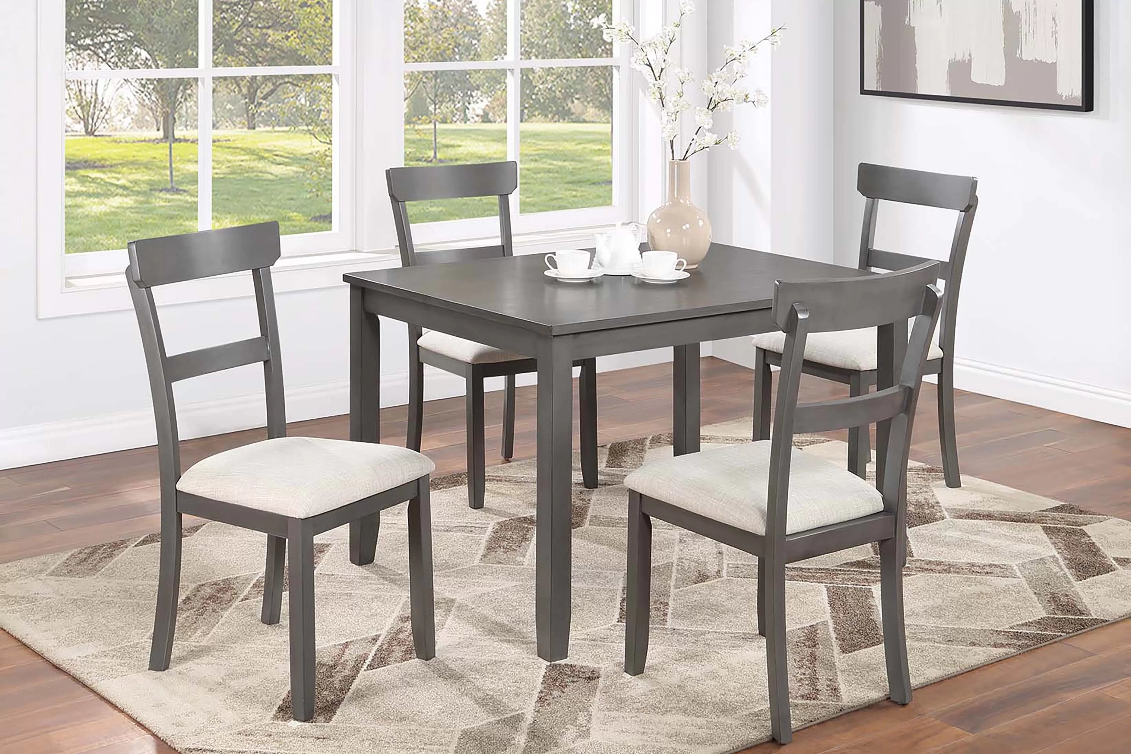 Dining room set with a table and four chairs in a well-lit room.