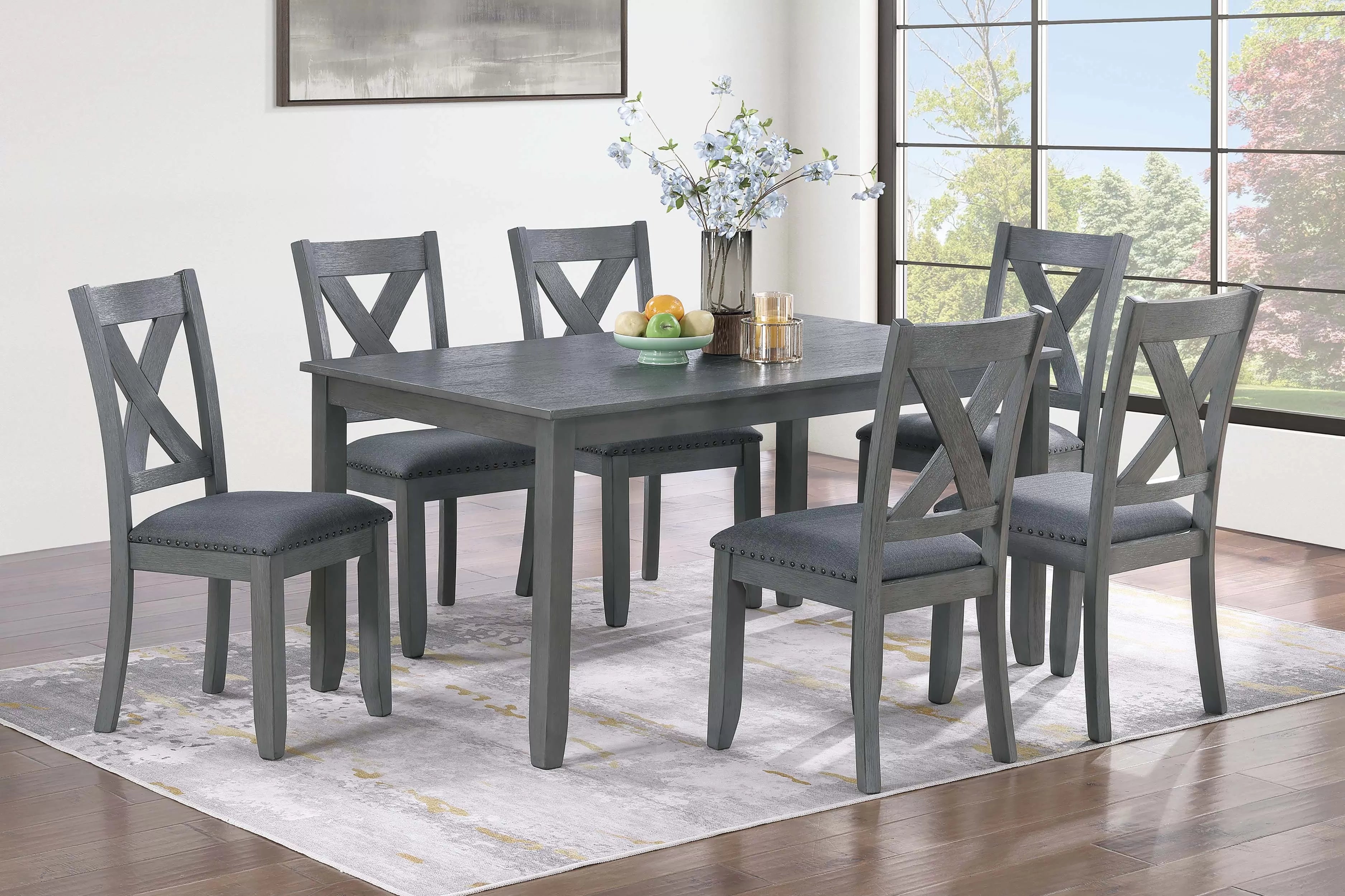 Gray dining table with six chairs in a room with large windows.