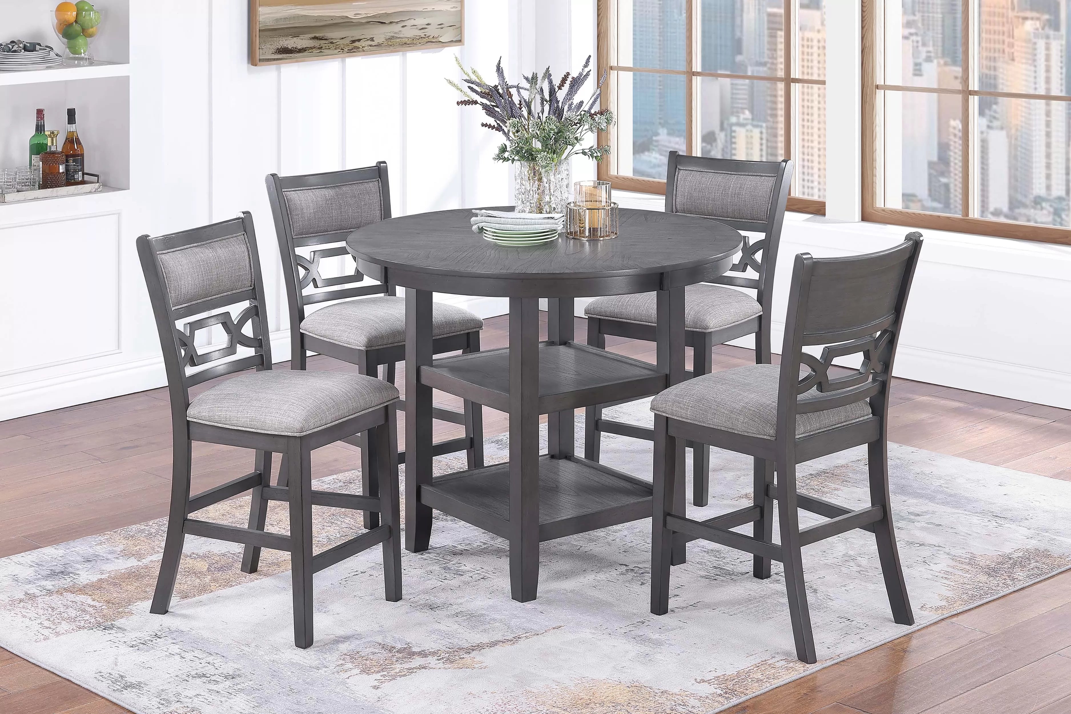 Dining set with round table and 4 chairs in a room with large windows.