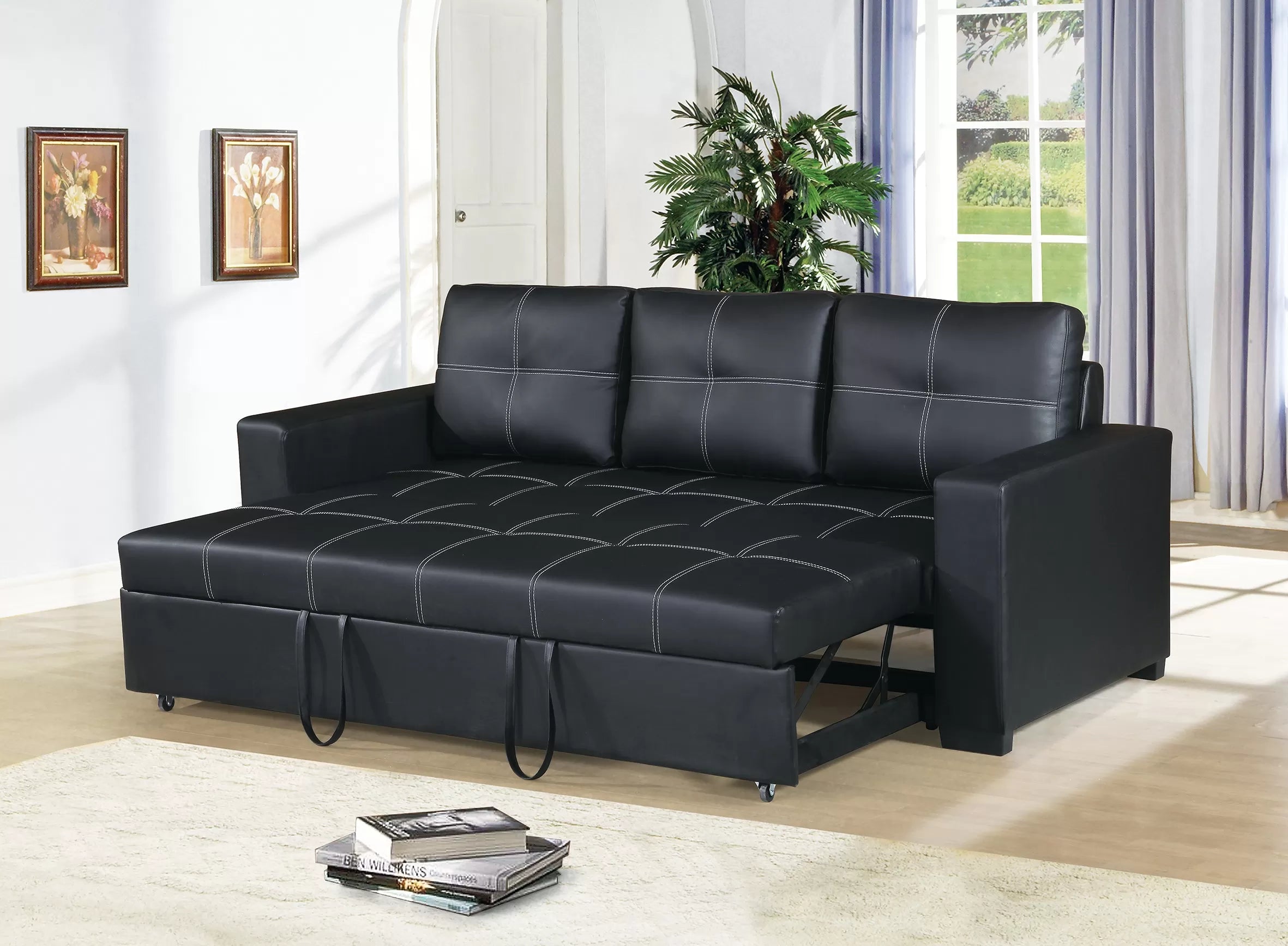 Black leather sofa bed in a living room setting with a plant and window in the background.