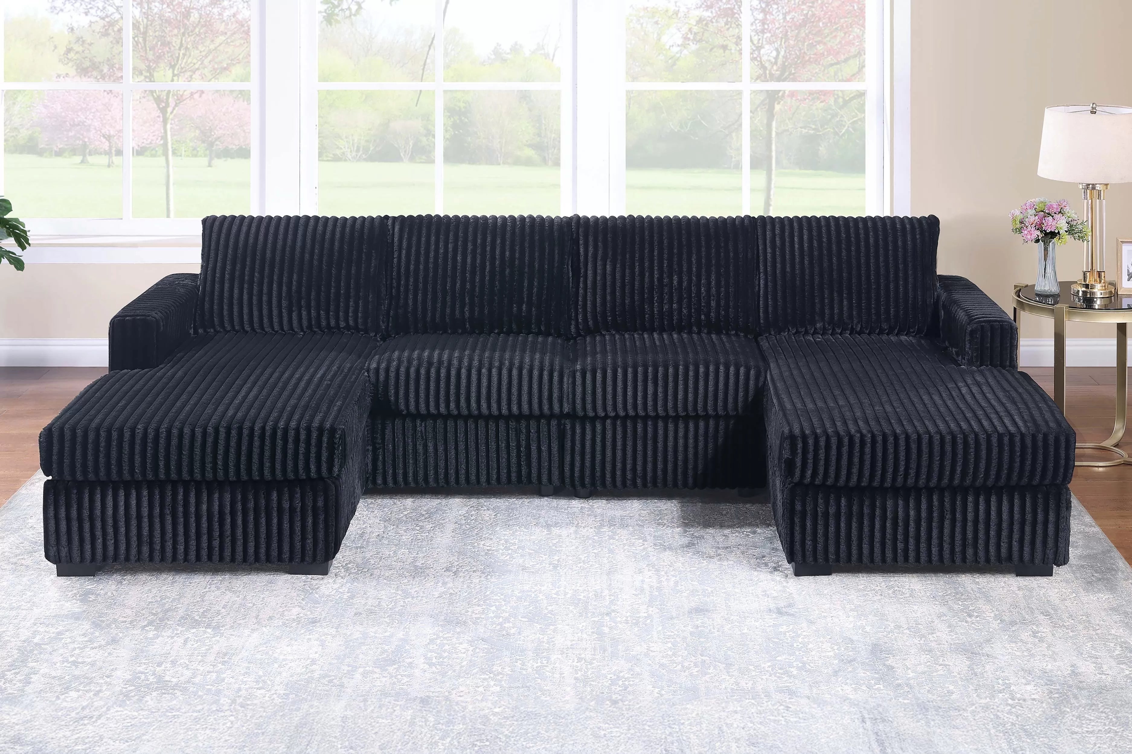 Black sectional sofa in a living room setting with large windows.