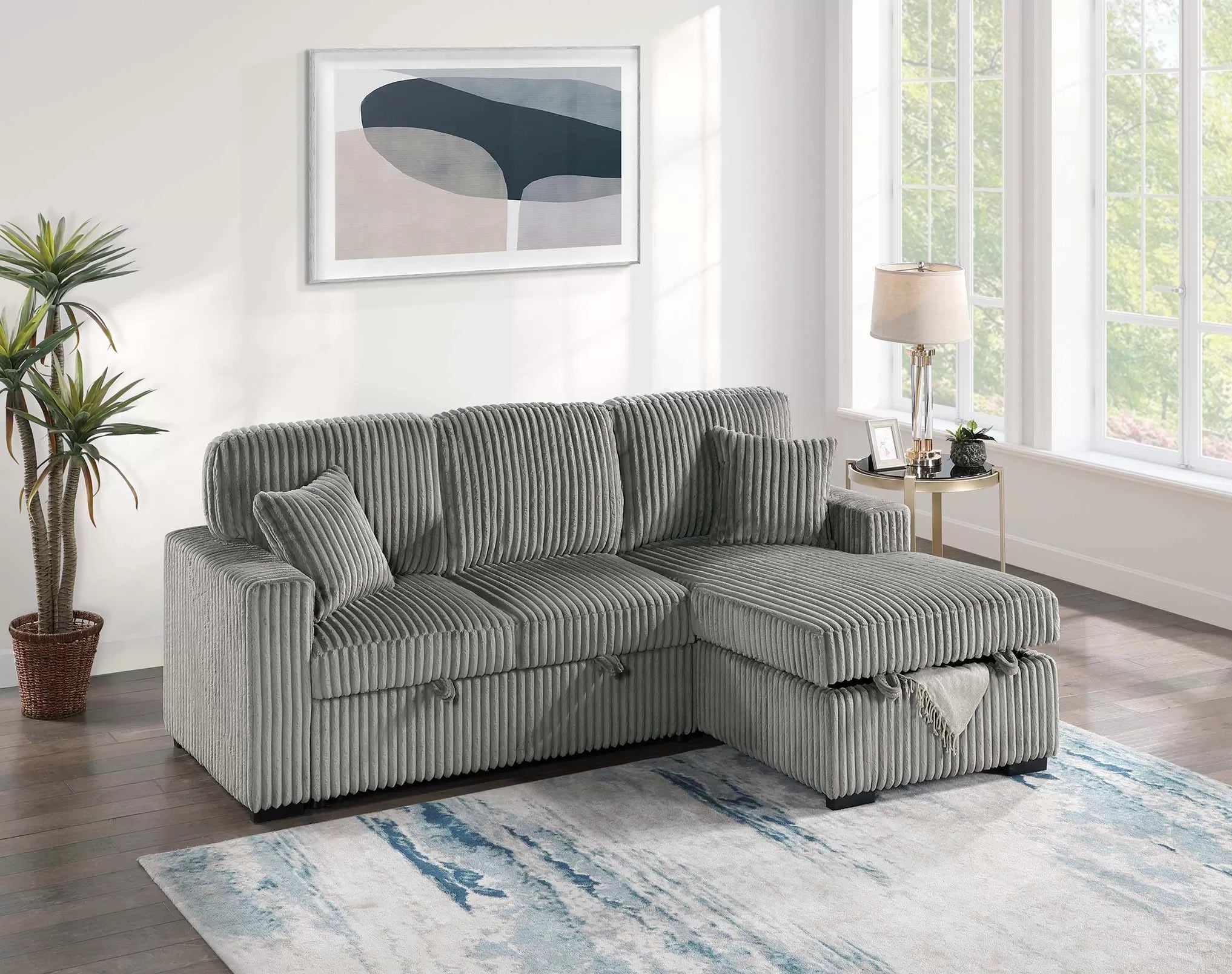 Gray striped sectional sofa in a living room with a plant, rug, and framed art on the wall.