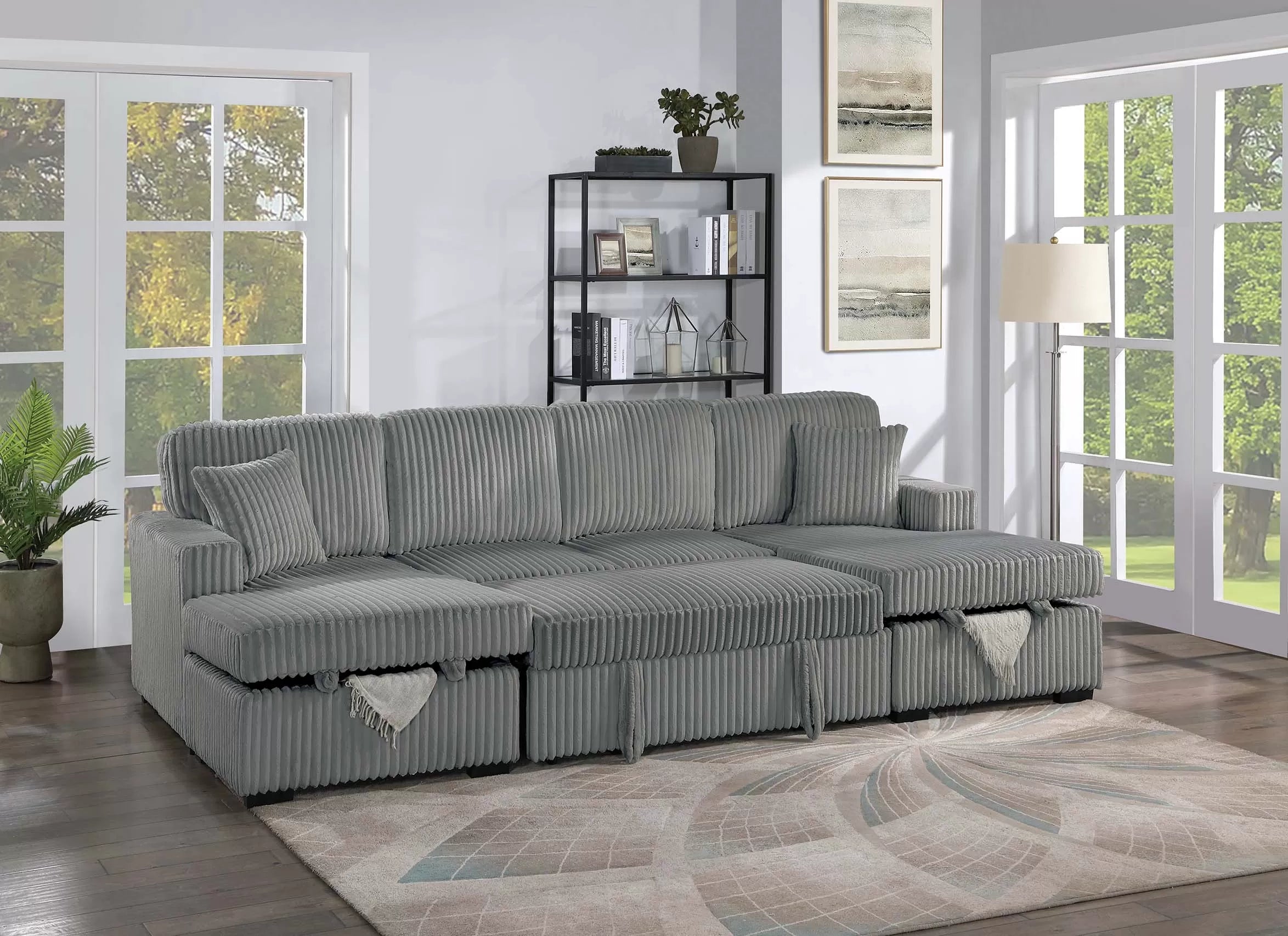 Gray sectional sofa with pullout extended in a living room with large windows and decor.