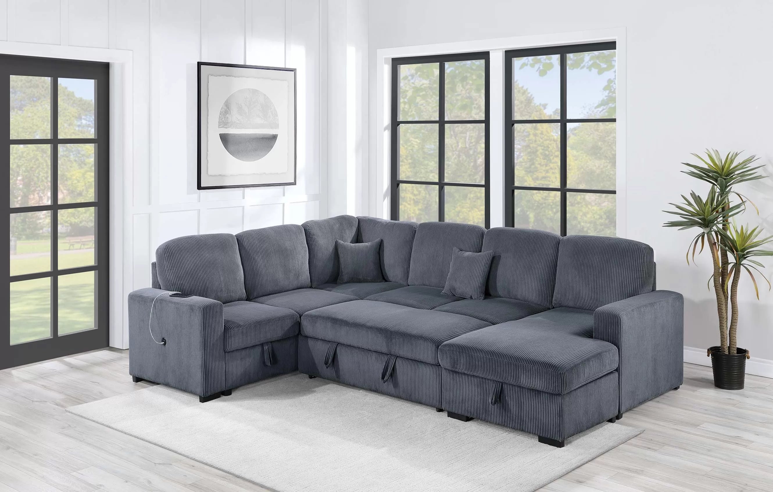 Gray sectional sofa in a living room with large windows and a plant.