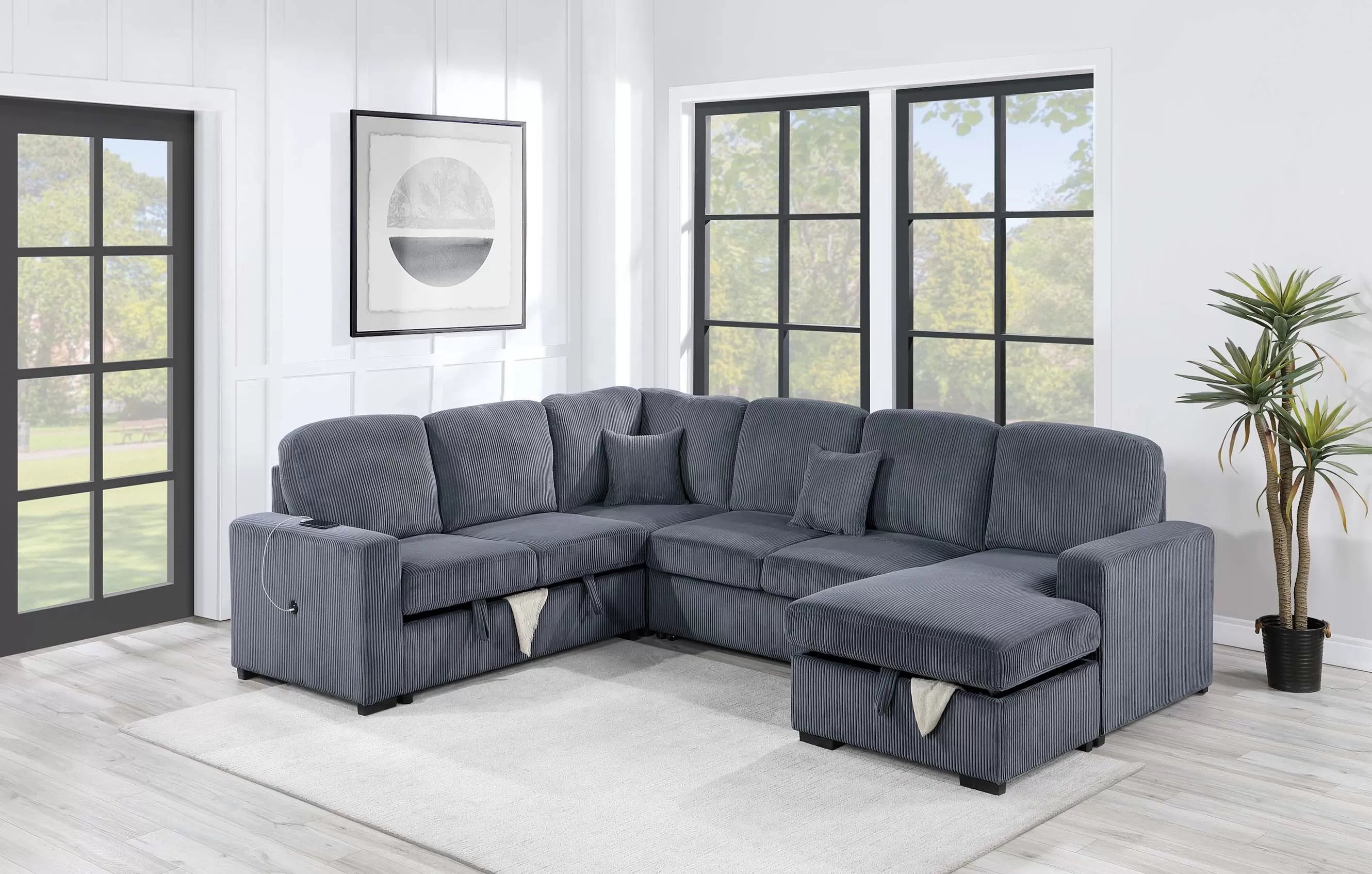 Gray sectional sofa in a living room with large windows and a plant.