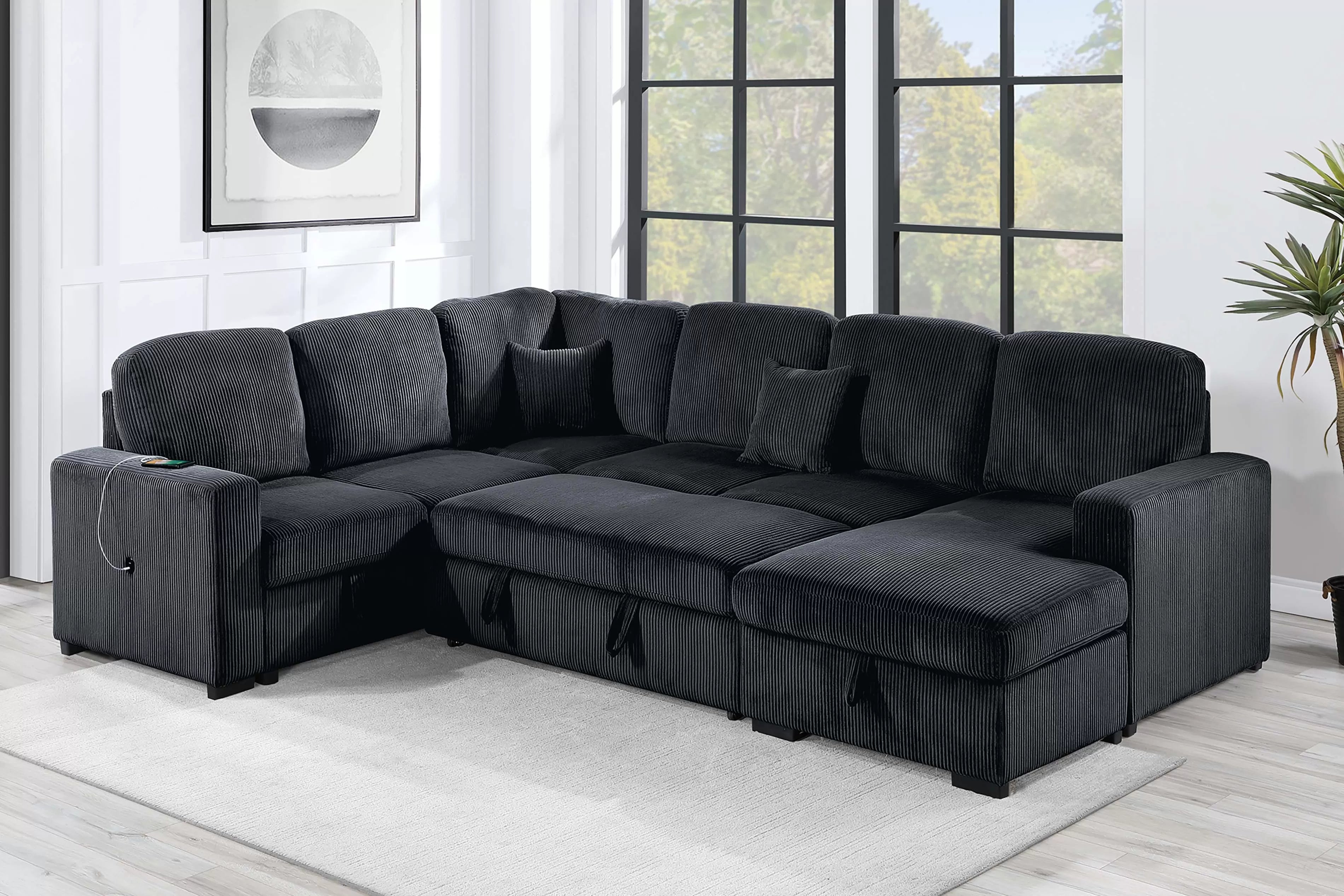 Gray sectional sofa in a living room with large windows and a plant.