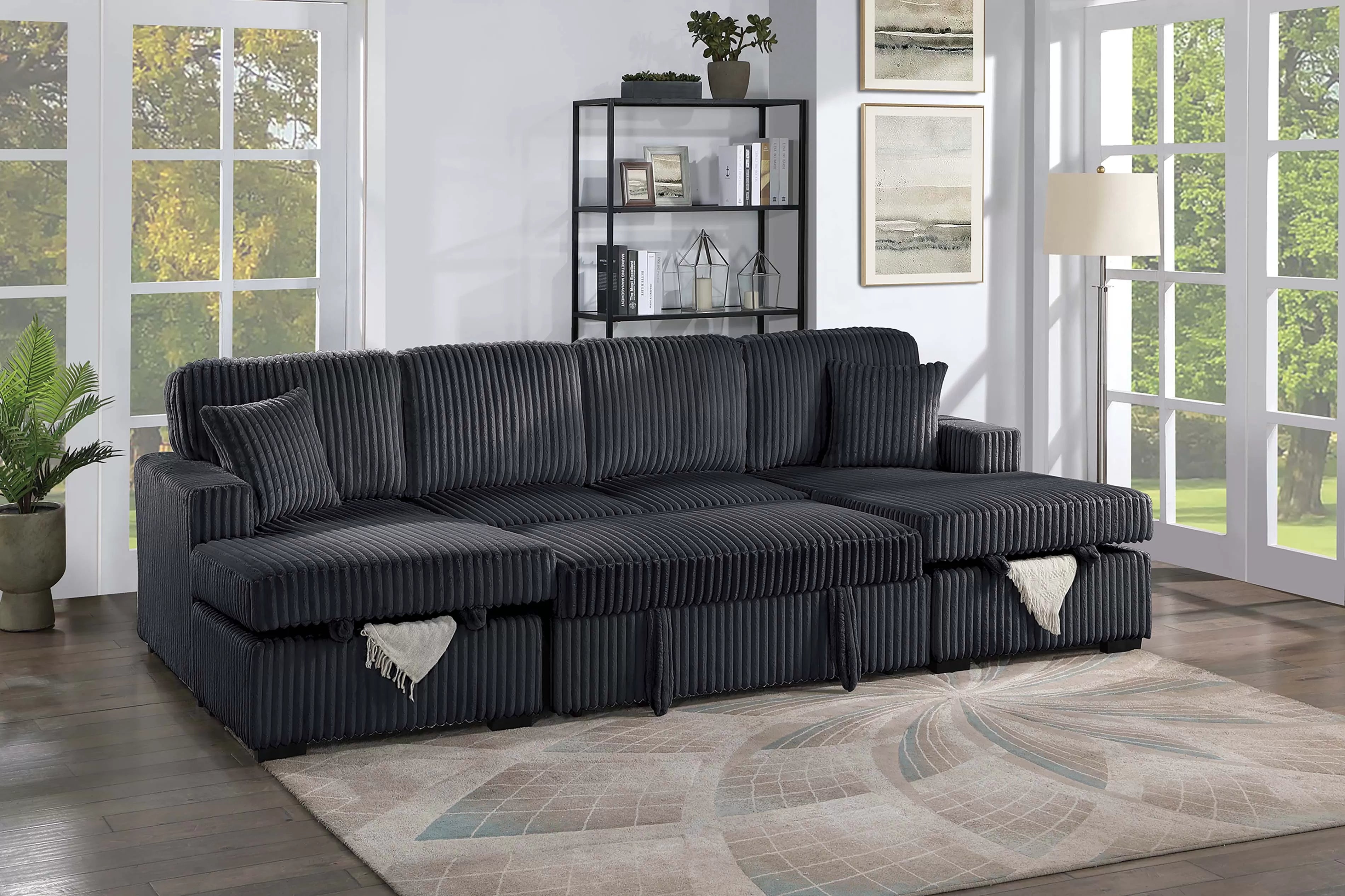 Black sectional sofa in a living room with large windows and decor.