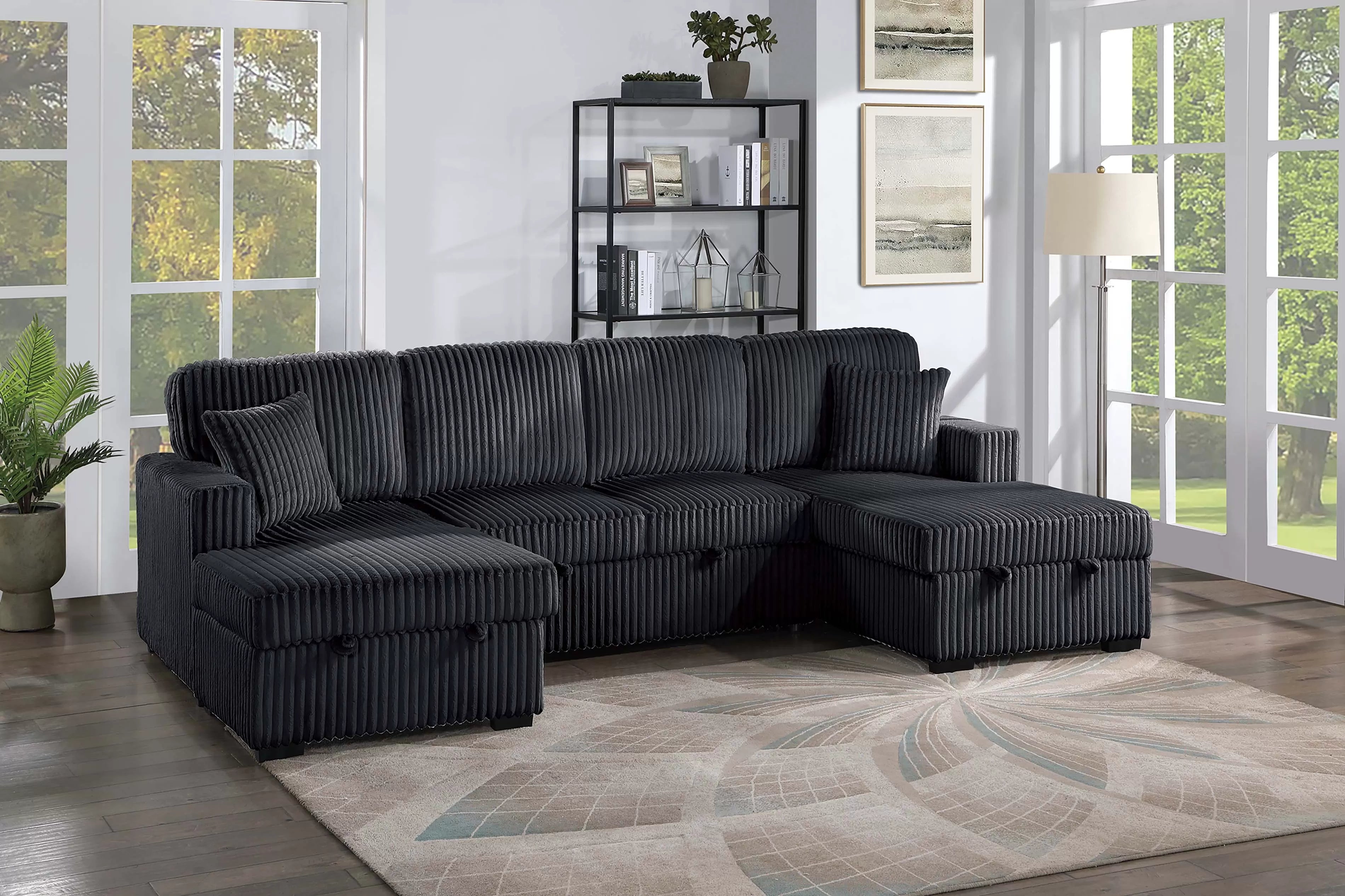 Black sectional sofa in a living room with large windows and decor.
