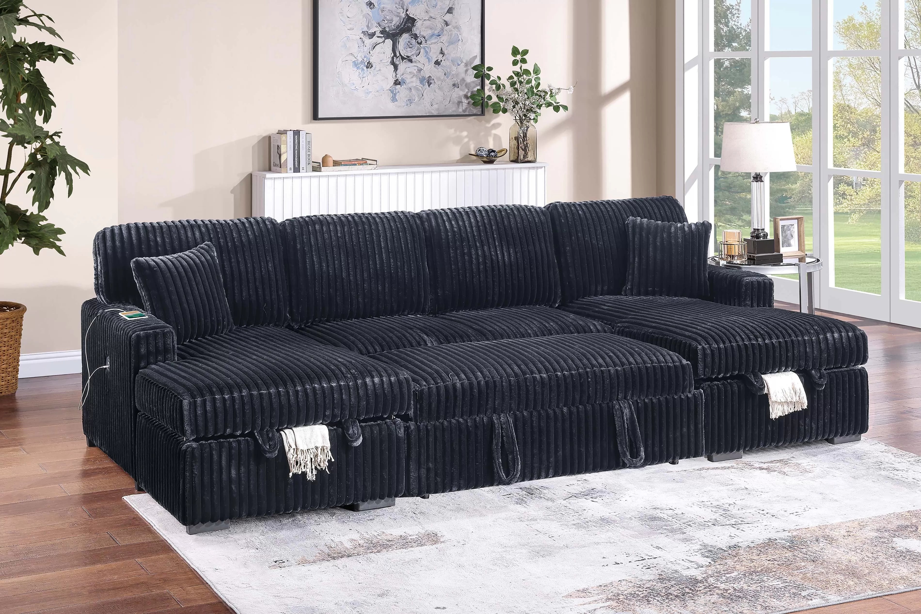 Black sectional sofa with pullout extended in a living room setting with decor elements.