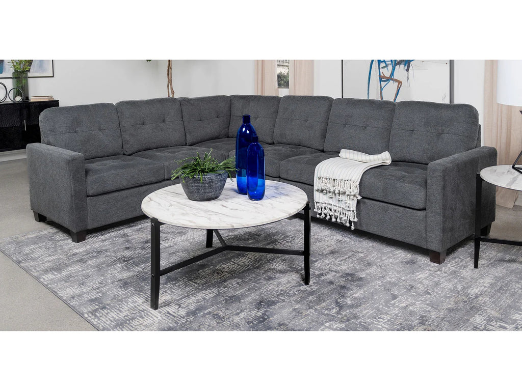 Gray sectional sofa with a marble coffee table in a living room setting.