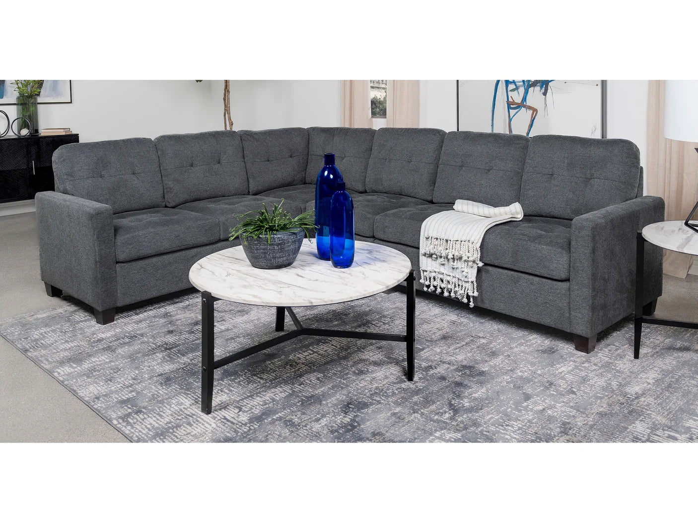 Gray sectional sofa with a marble coffee table in a living room setting.