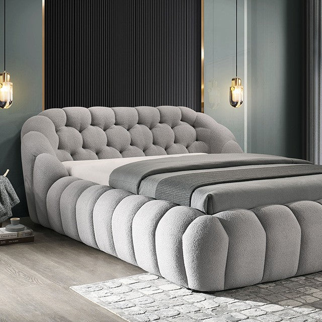 Gray upholstered bed in a modern bedroom setting with decorative wall lights.