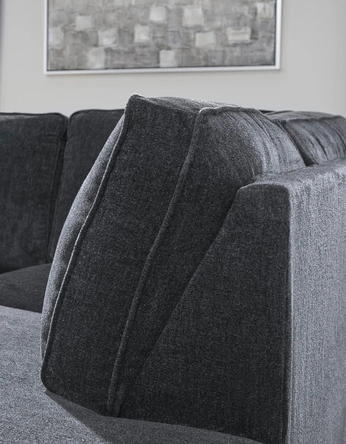 Gray sectional sofa with a textured wall and abstract painting in the background