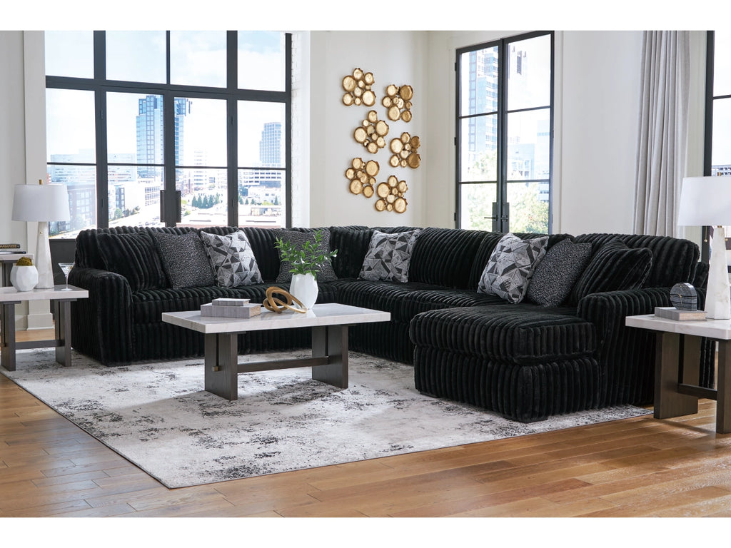 Black sectional sofa in a modern living room with large windows and decorative wall art.