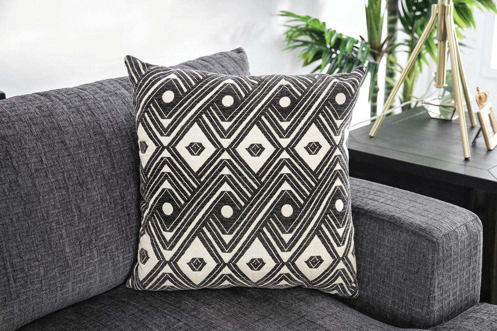 Decorative pillow with dary gray and white pattern on a gray sofa