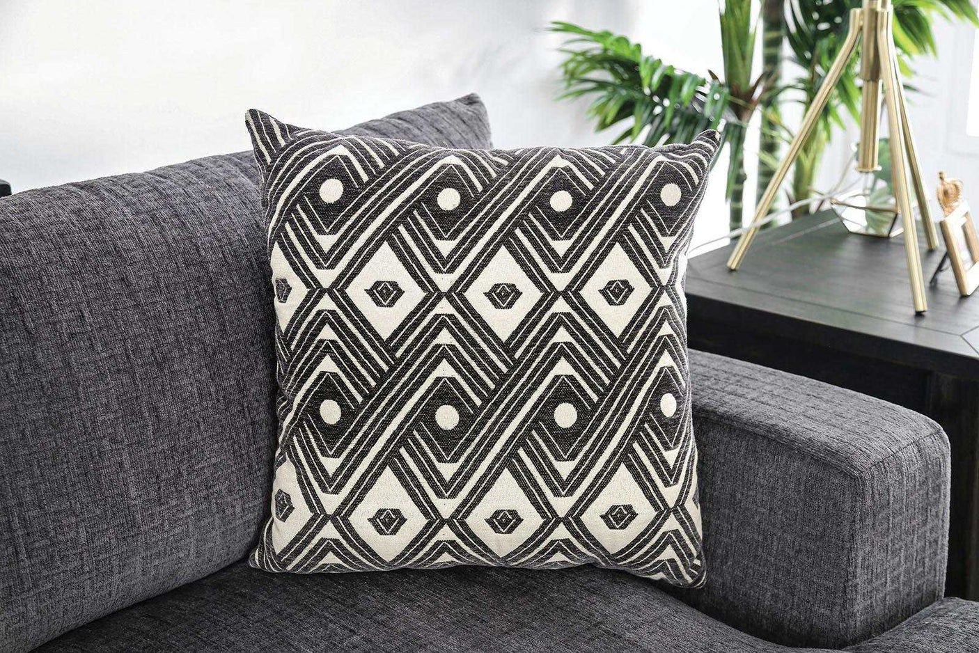 Decorative pillow with dary gray and white pattern on a gray sofa