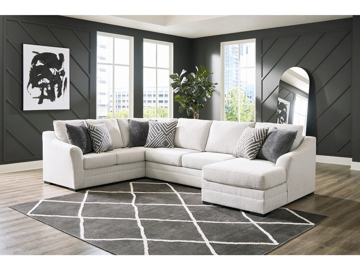 White sectional sofa in a living room with dark walls and a patterned rug.