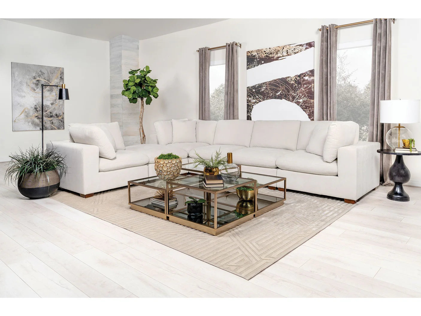 Modern living room with a ivory sectional sofa, glass coffee table, and decorative elements.