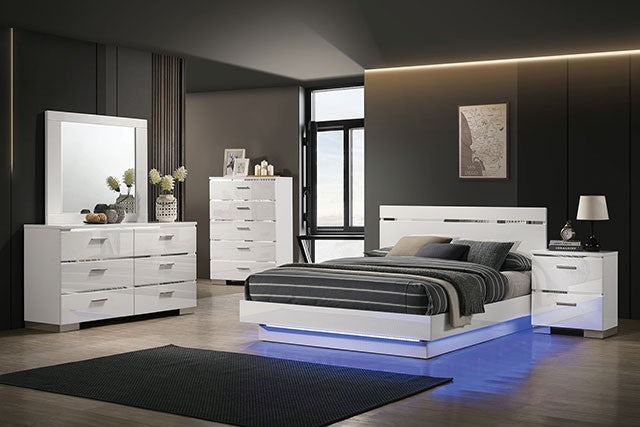 Modern bedroom set with white furniture including bed, dresser, and nightstands in a dark-themed room.