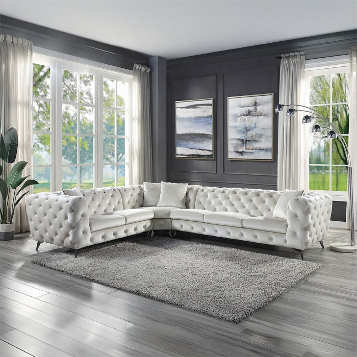Modern living room with a white tufted sectional sofa, gray rug, and large windows.