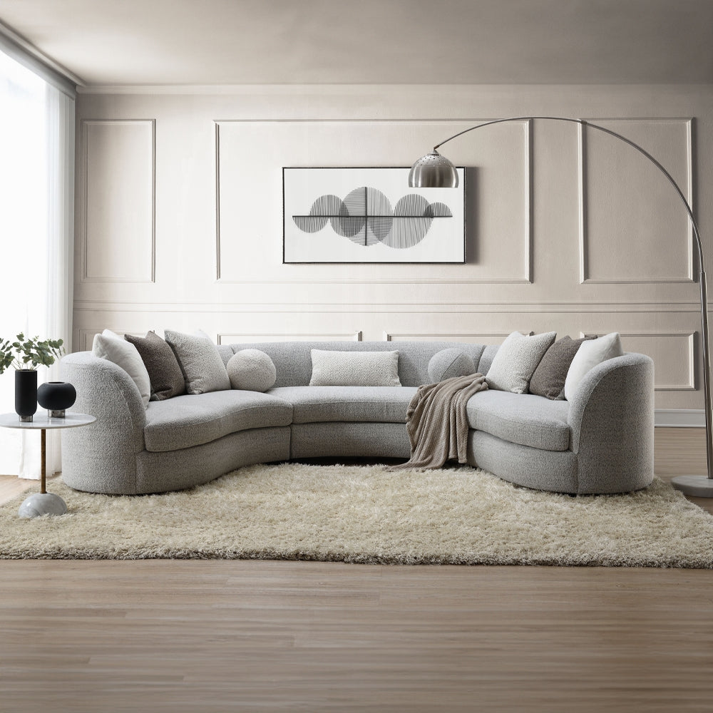 Gray sectional sofa in a living room with a rug and wall art.