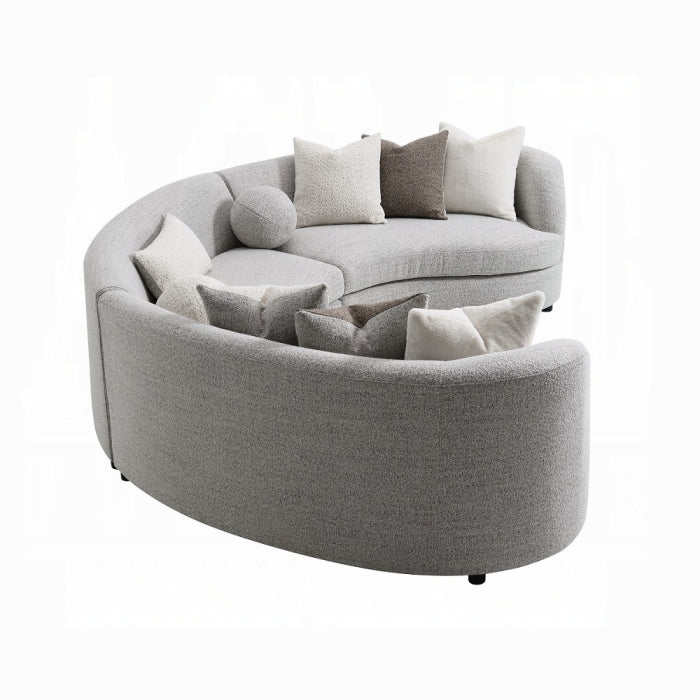 Gray curved sofa with multiple cushions on a white background