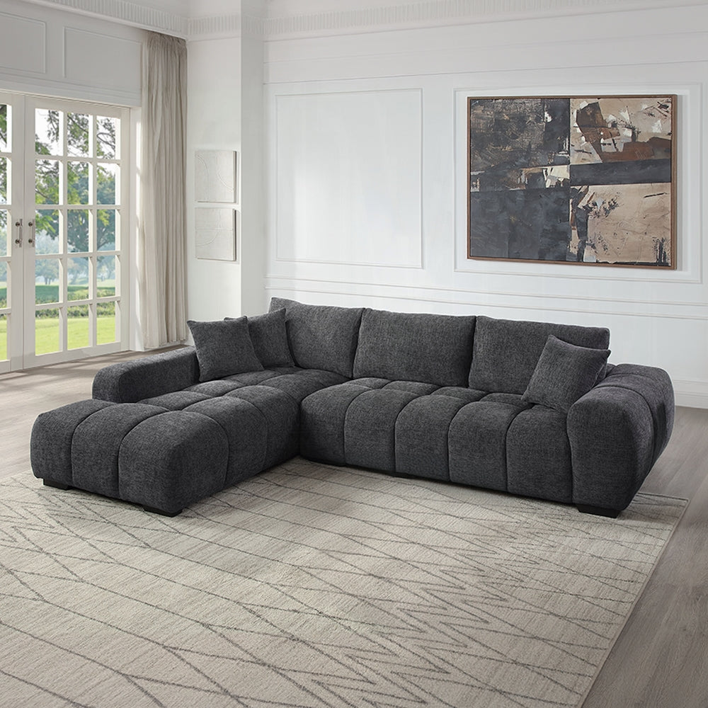 Gray sectional sofa in a living room with a painting on the wall.